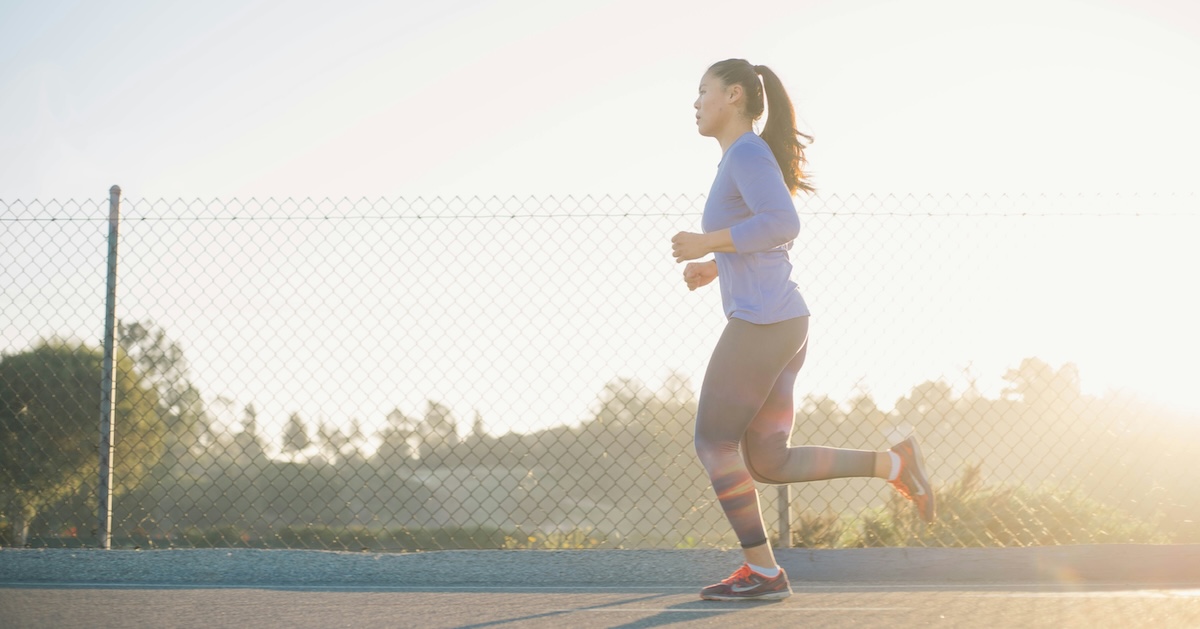 woman jogging near wire fence in a pair of running shoes