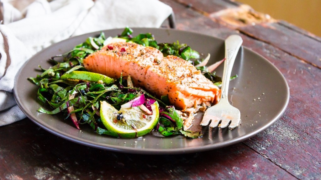 A green salad topped with baked salmon on a plate on a wooden table