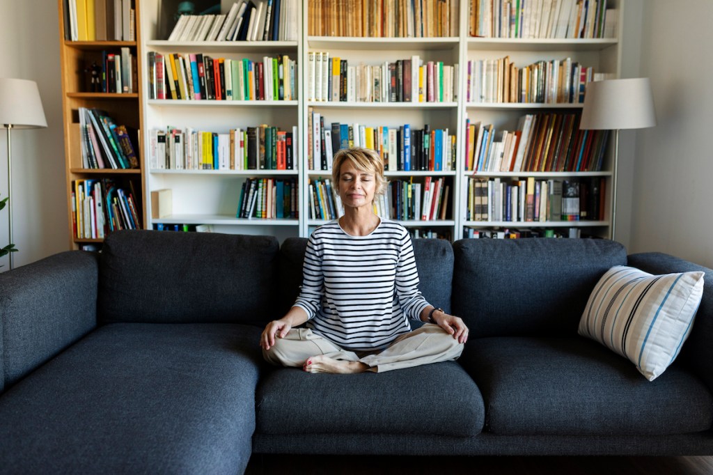 Woman meditating on couch to learn how to stop worrying about things you can't control