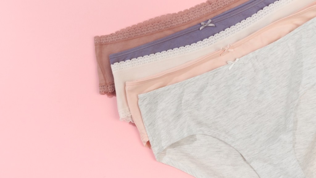 Five pairs of cotton underwear in assorted colors, which can ease symptoms of a vaginal ulcer, against a pink background