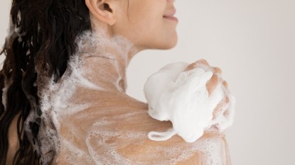 woman using body wash and loofah