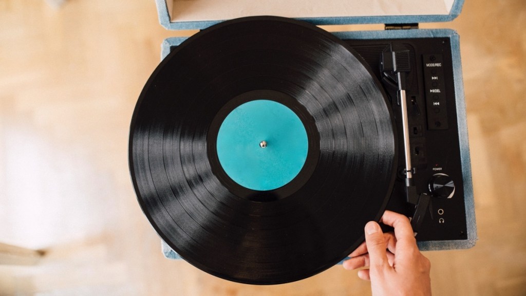 A close-up of a woman's hand placing a record on a record player to trigger neural nostalgia