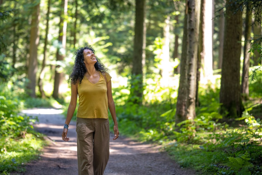Woman practicing mindfulness for beginners by looking at nature as she goes for a walk
