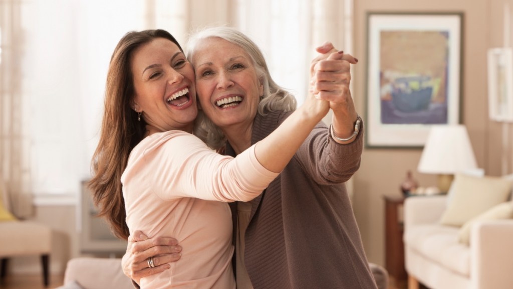 A mature woman dancing with her adult daughter at home