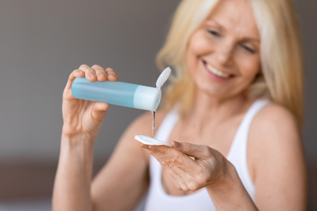 mature woman pouring toner on cotton pad