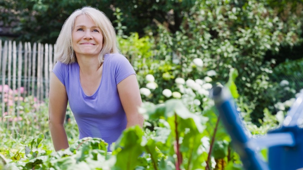 A woman in a purple shirt smiling while in a veggie garden