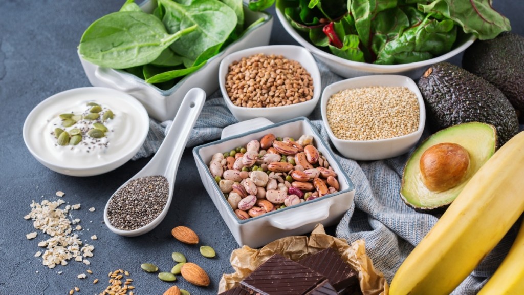 As assortment of magnesium-rich foods, such as bananas, leafy greens, nuts, seeds, yogurt and chocolate, all of which can help treat fibromyalgia