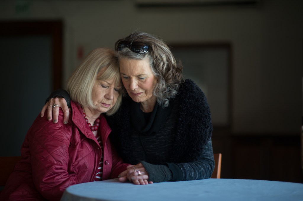 Two women comforting one another at table for how to comfort someone who's grieving