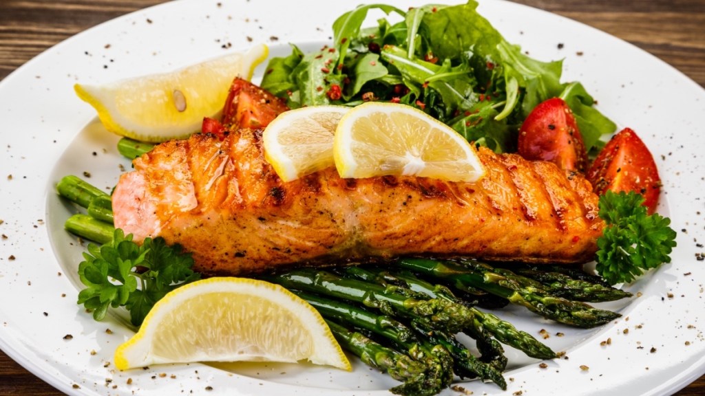 Baked salmon, which is rich in the omega 3 you need per day, with lemon and asparagus on a white plate
