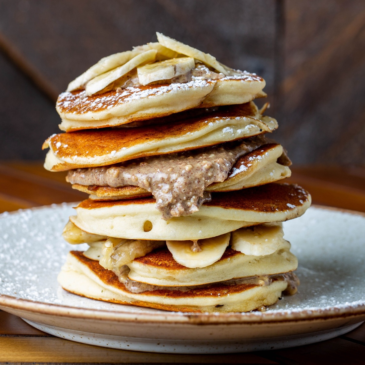 Stack of The Rock's famous coconut banana pancakes with peanut butter and maple syrup