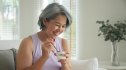 A smiling woman eating yogurt to help get rid of brain fog