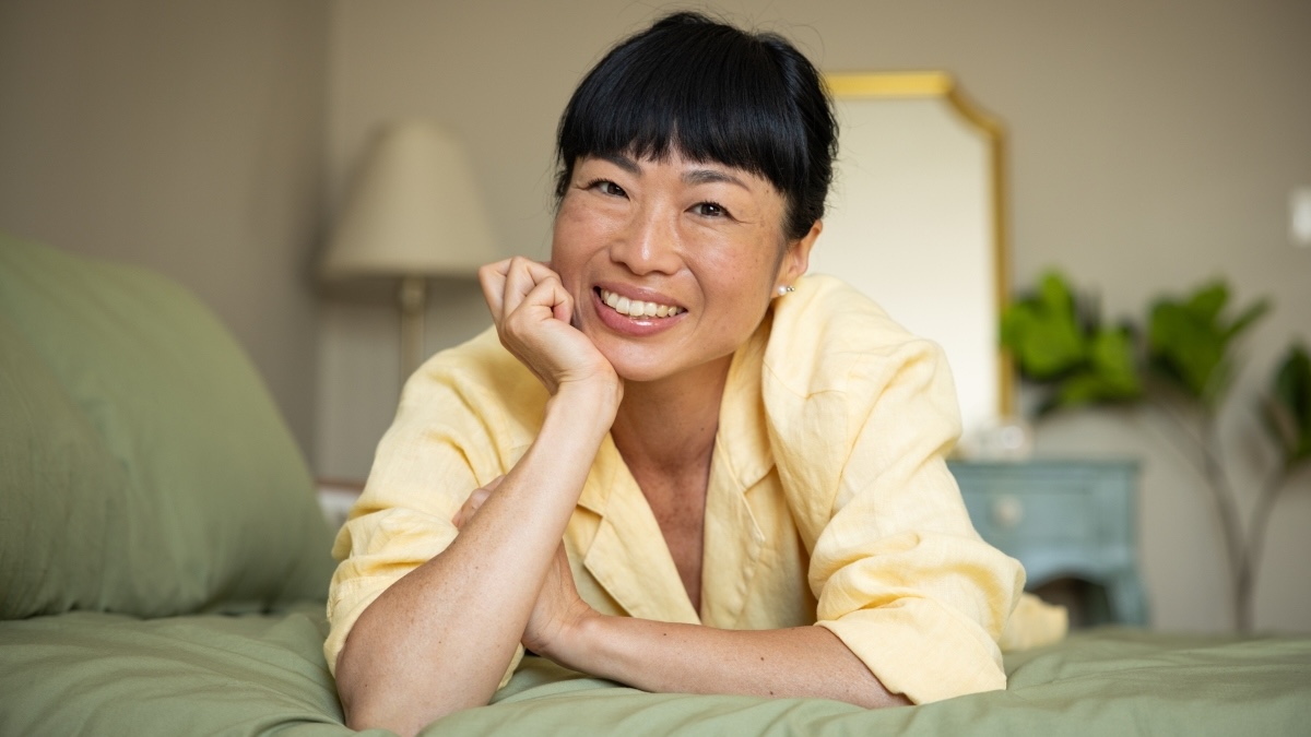A woman in a yellow top smiling after learning how to reduce stress