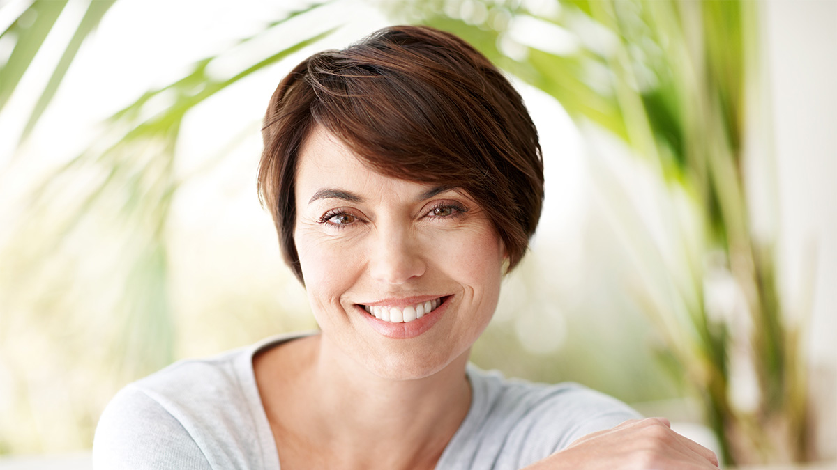 Woman smiling with thick, full and shiny hair after learning how hyaluronic acid for hair can help