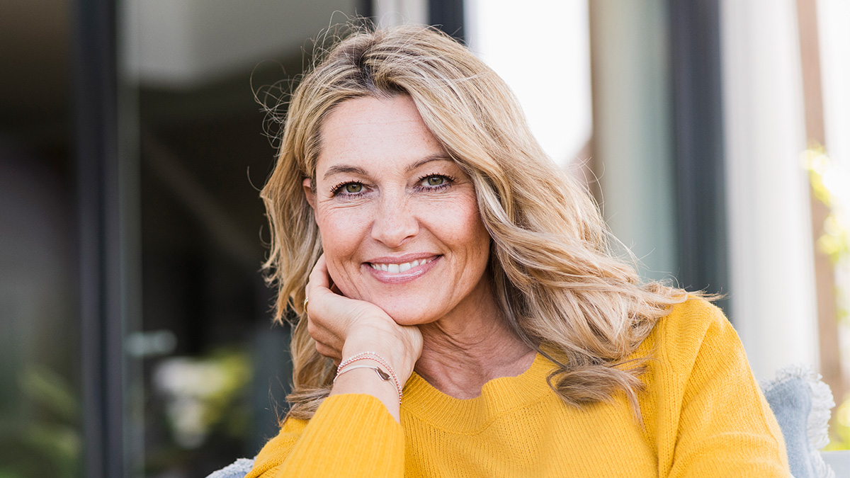 Woman smiling with bright blonde hair after learning how to use hair lightener