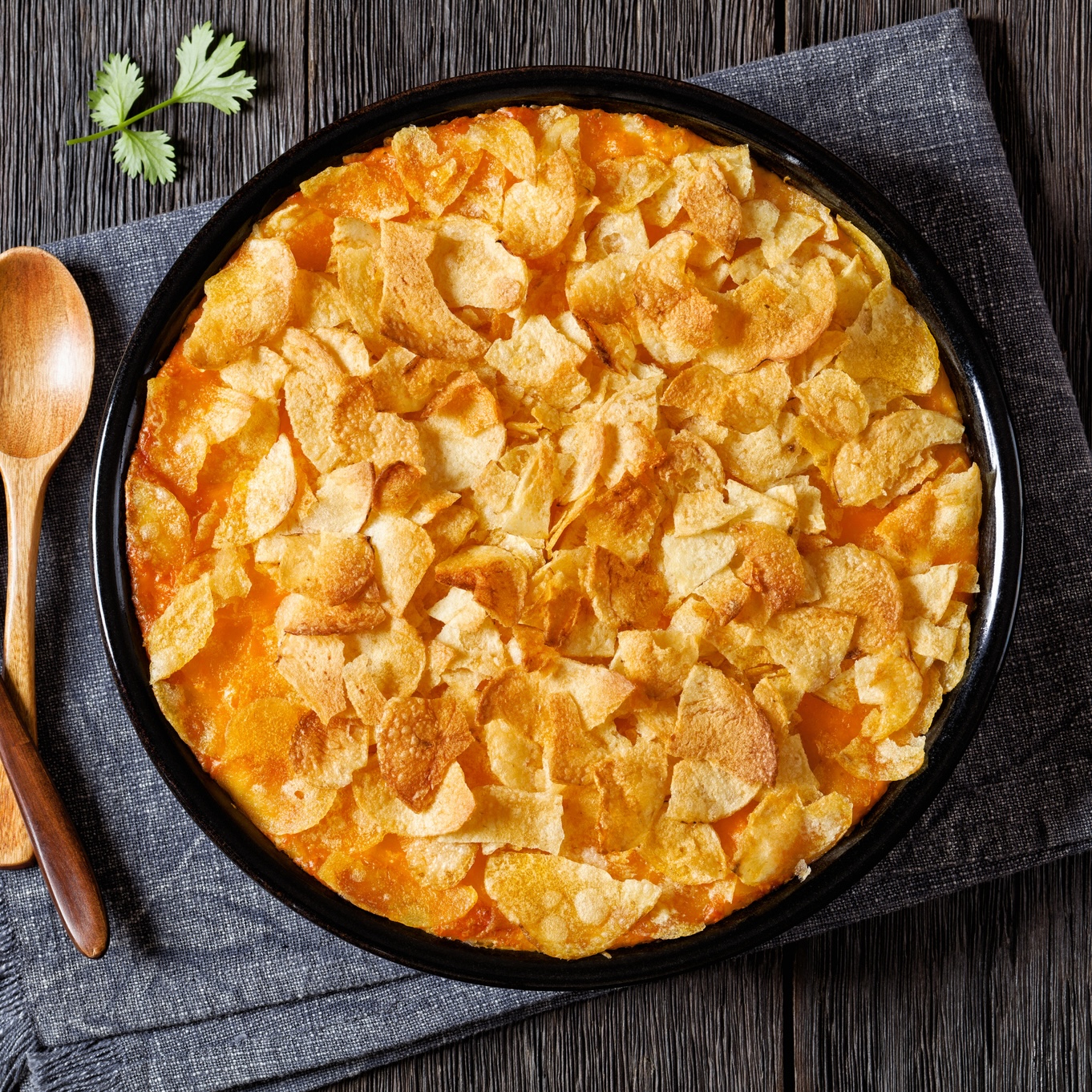 top view of seafood casserole with potato chip topping in skillet with wooden spoons