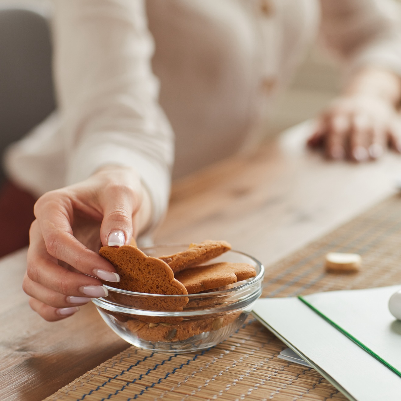 mature woman with food cravings reaching for cookies while working
