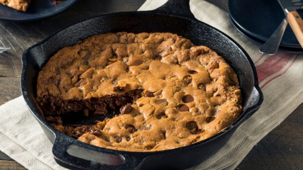 skillet brookie with slice cut out in pan after baking