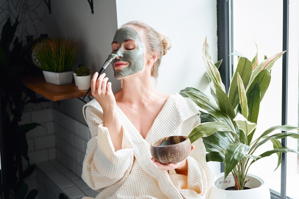 mature woman applying face mask for an at home spa day