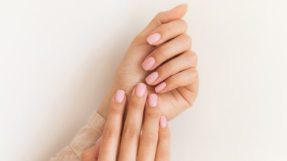 A woman's hands with pale pink nail polish after curing an infected hangnail