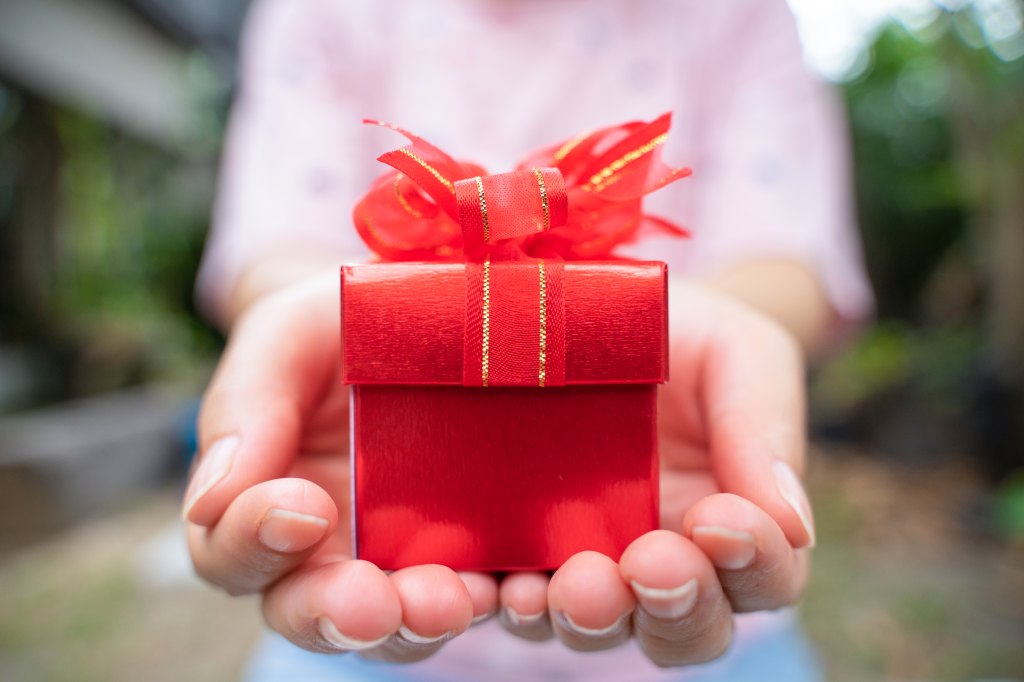 Close up of a woman holding a red gift box (imposter syndrome) 