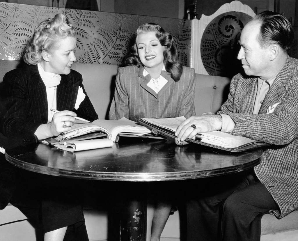 GILDA, from left, script girl Dorothy Cummings, Rita Hayworth, dialogue director Harold Clifton, running lines on-set, 1946