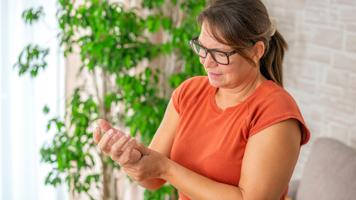 middle-aged woman holds her painful wrist as she she feels carpal tunnel pain