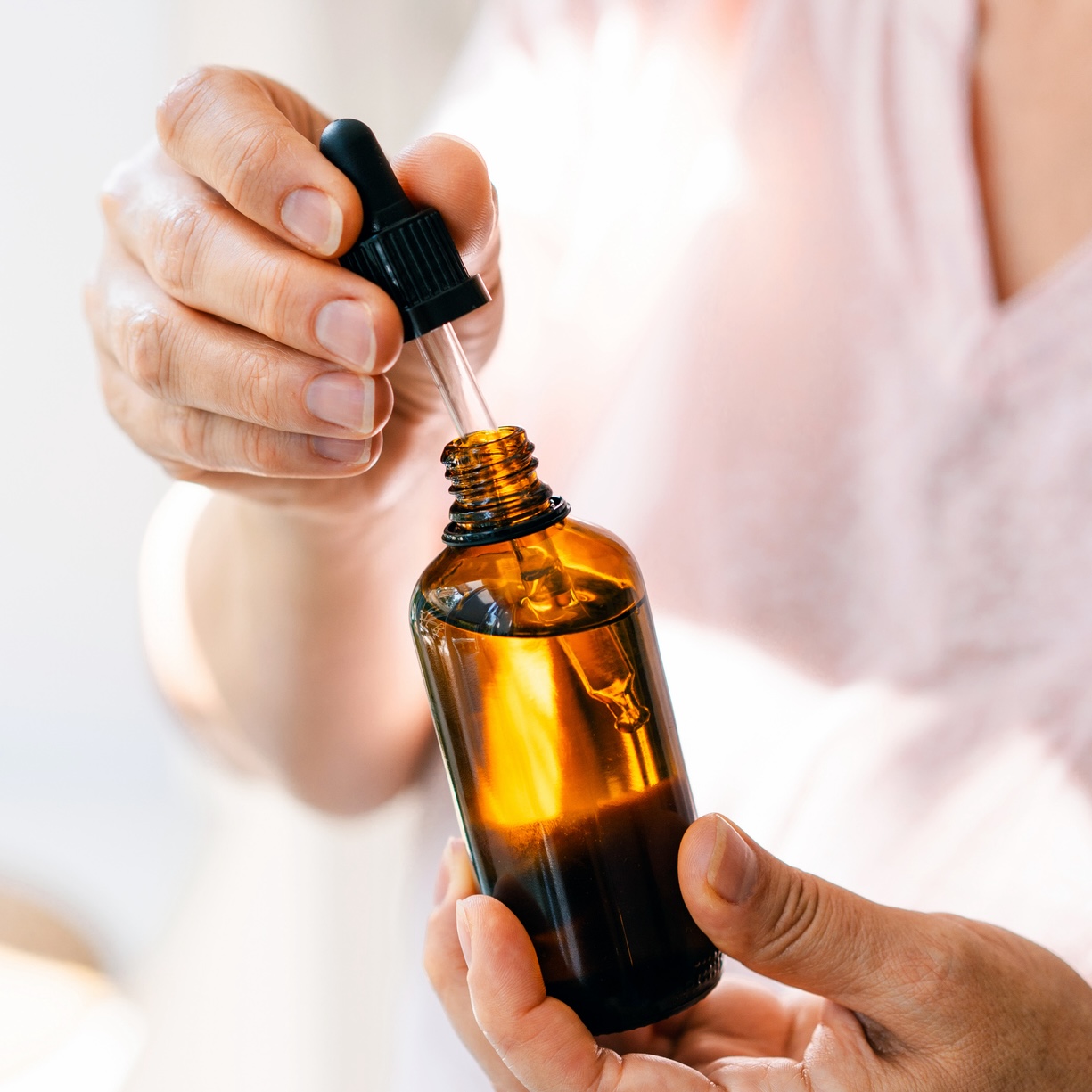 mature woman holding bottle of castor oil for eyes