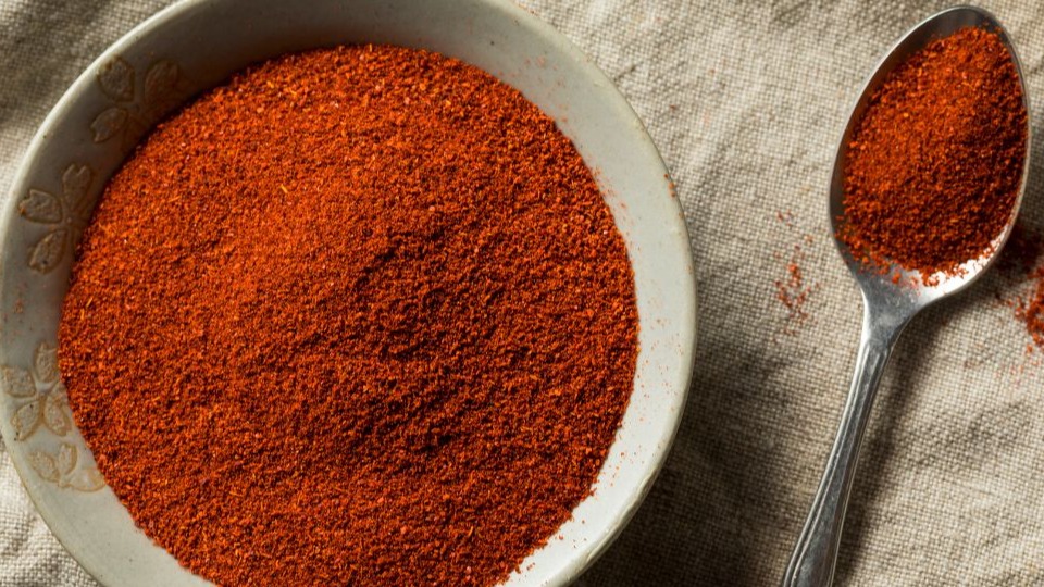 Dry red smoked paprika in a bowl and spoonful