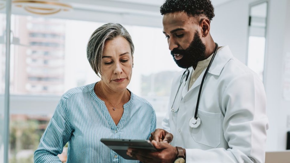 woman and her doctor looking at tablet planning alzheimer’s disease treatment