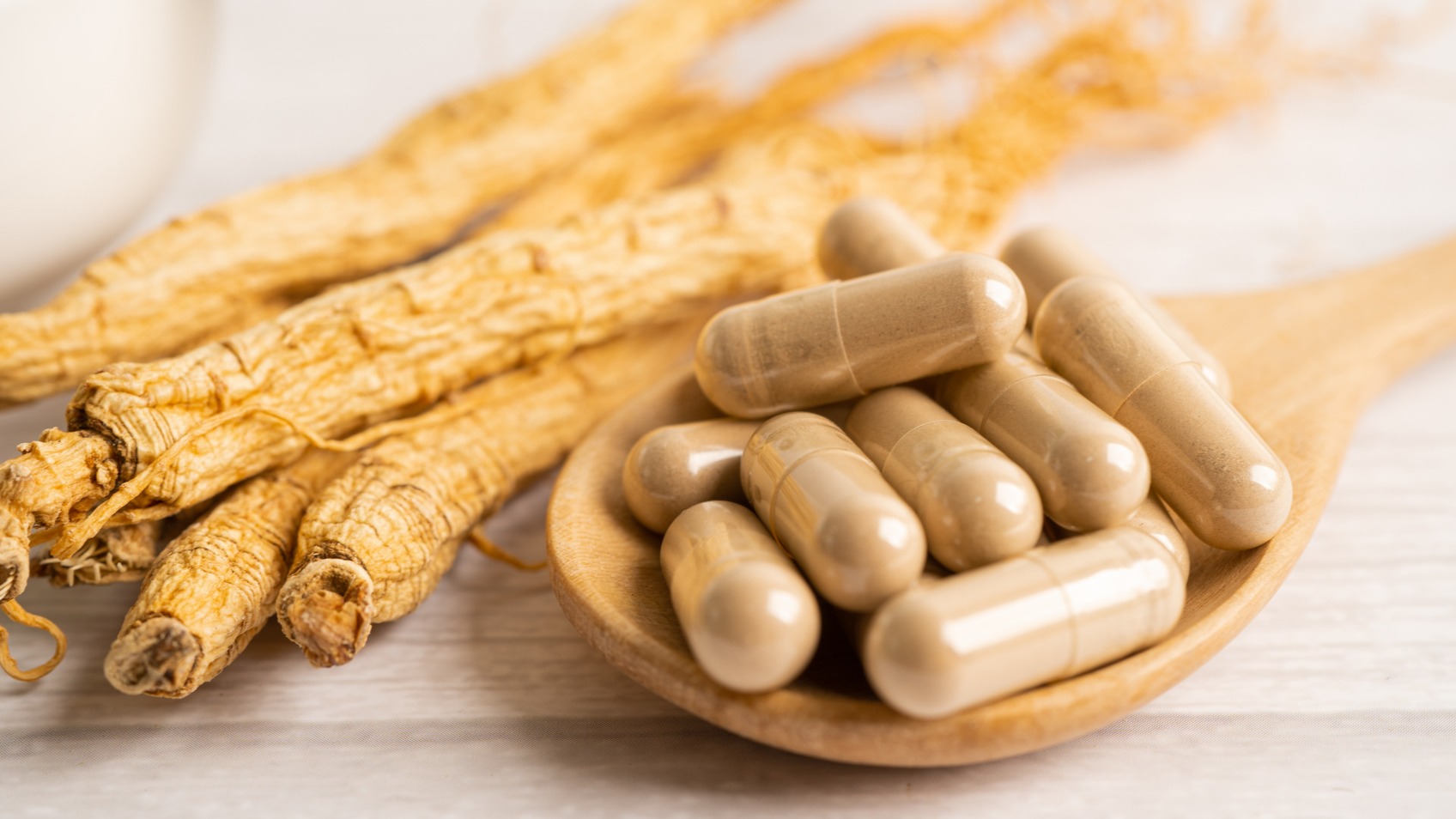 Ginseng root and capsules in wooden spoon for anxiety