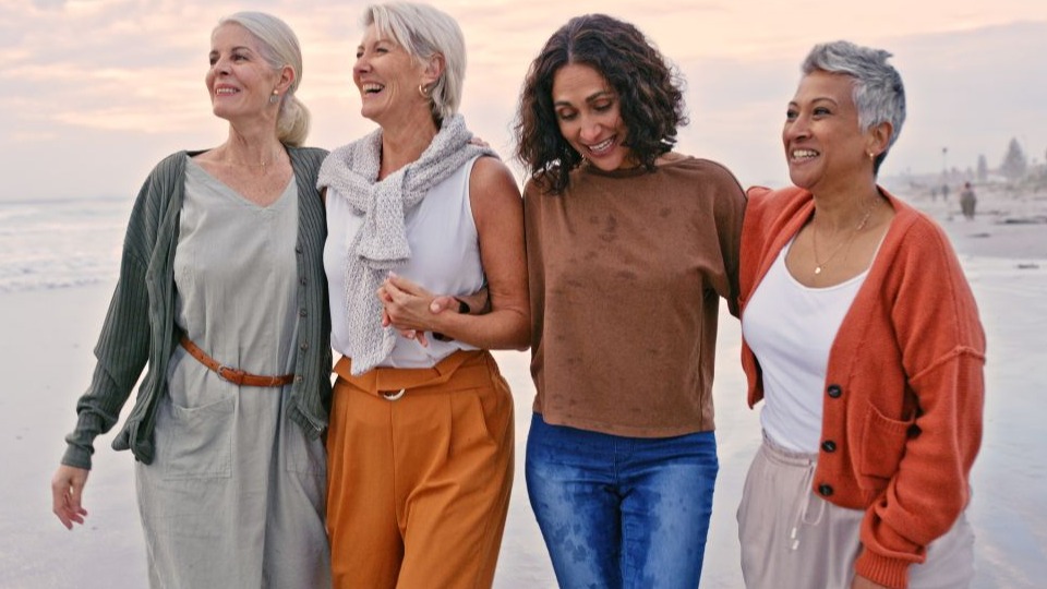 group of women walking on a beach together laughing and smiling, which is one of the habits the prevent cognitive decline
