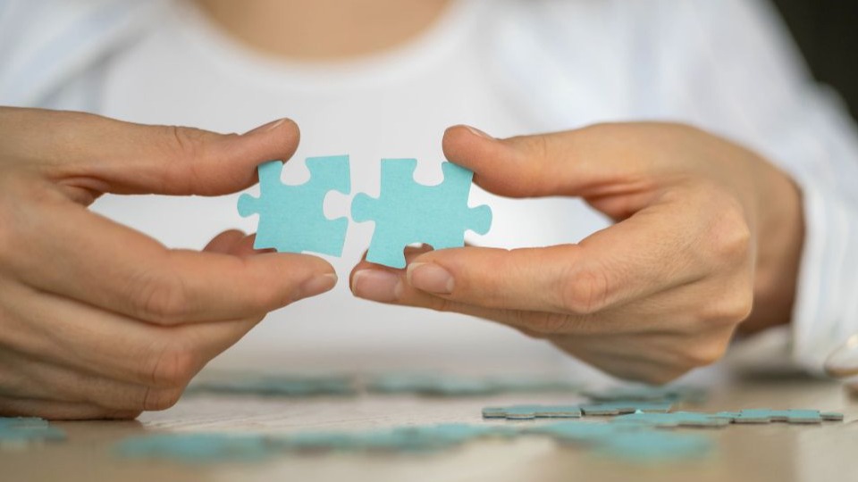 closeup of woman's hand holding puzzle pieces