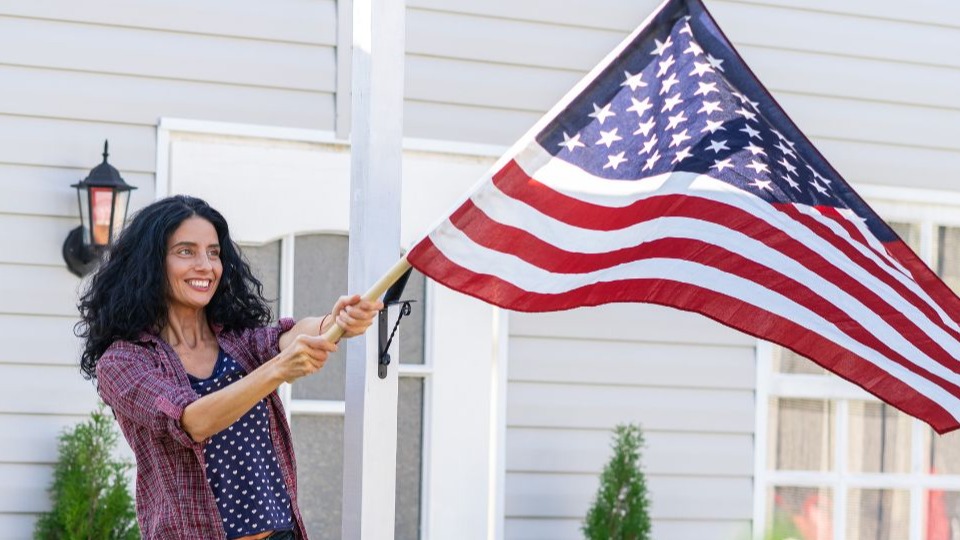 woman hangs a american flag on her porch