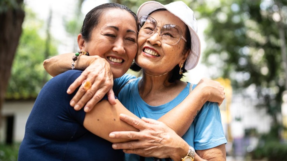 Mother and daughter embracing and smiling outdoors