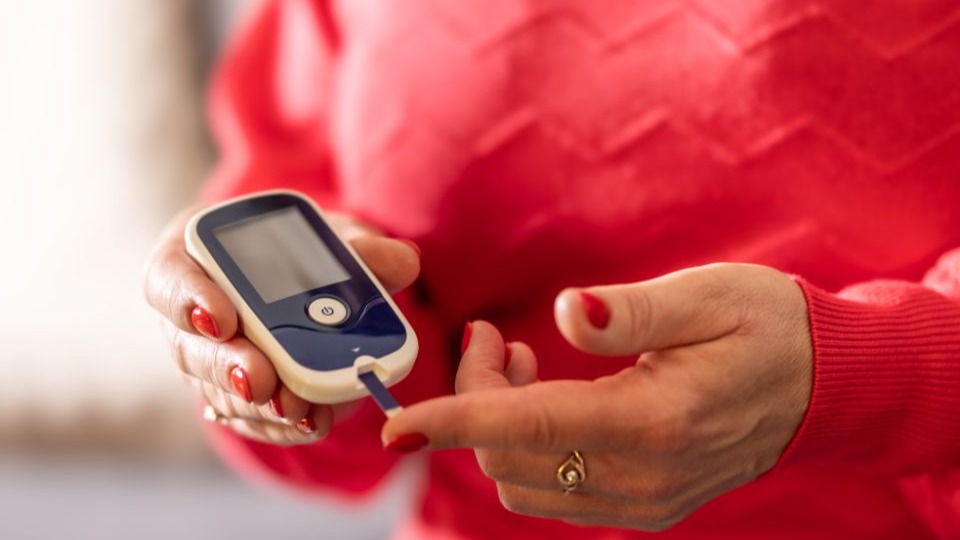 Closeup of woman checking blood sugar levels with glucose meter to prick finger