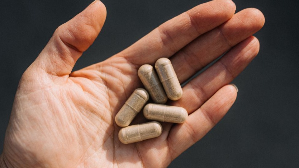 hand holding light brown capsules of supplements to lower blood sugar