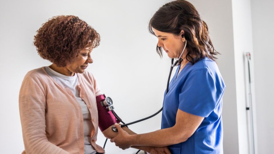 Nurse checking woman's blood pressure in exam room