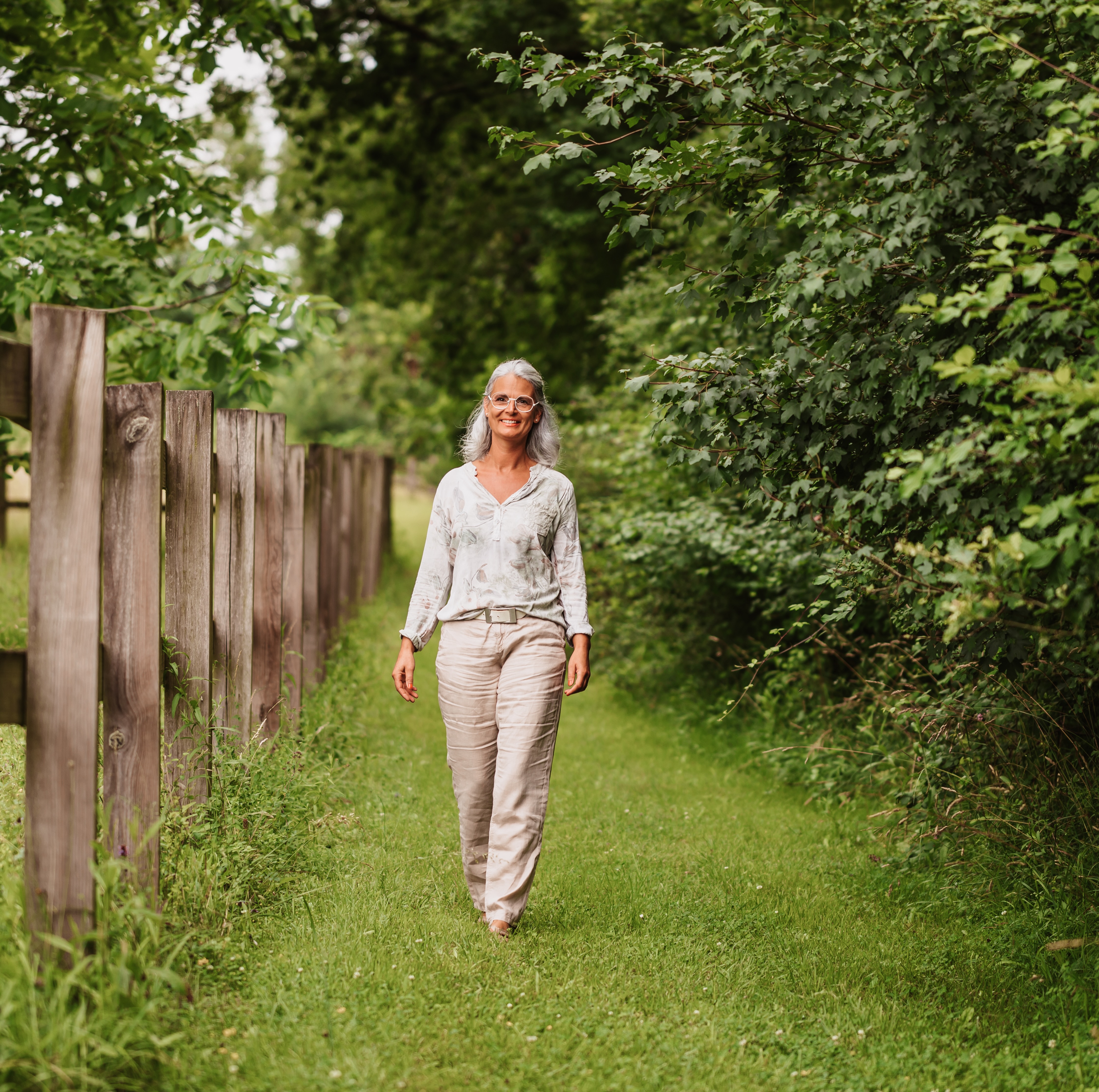 woman smiling walking through greenery outside