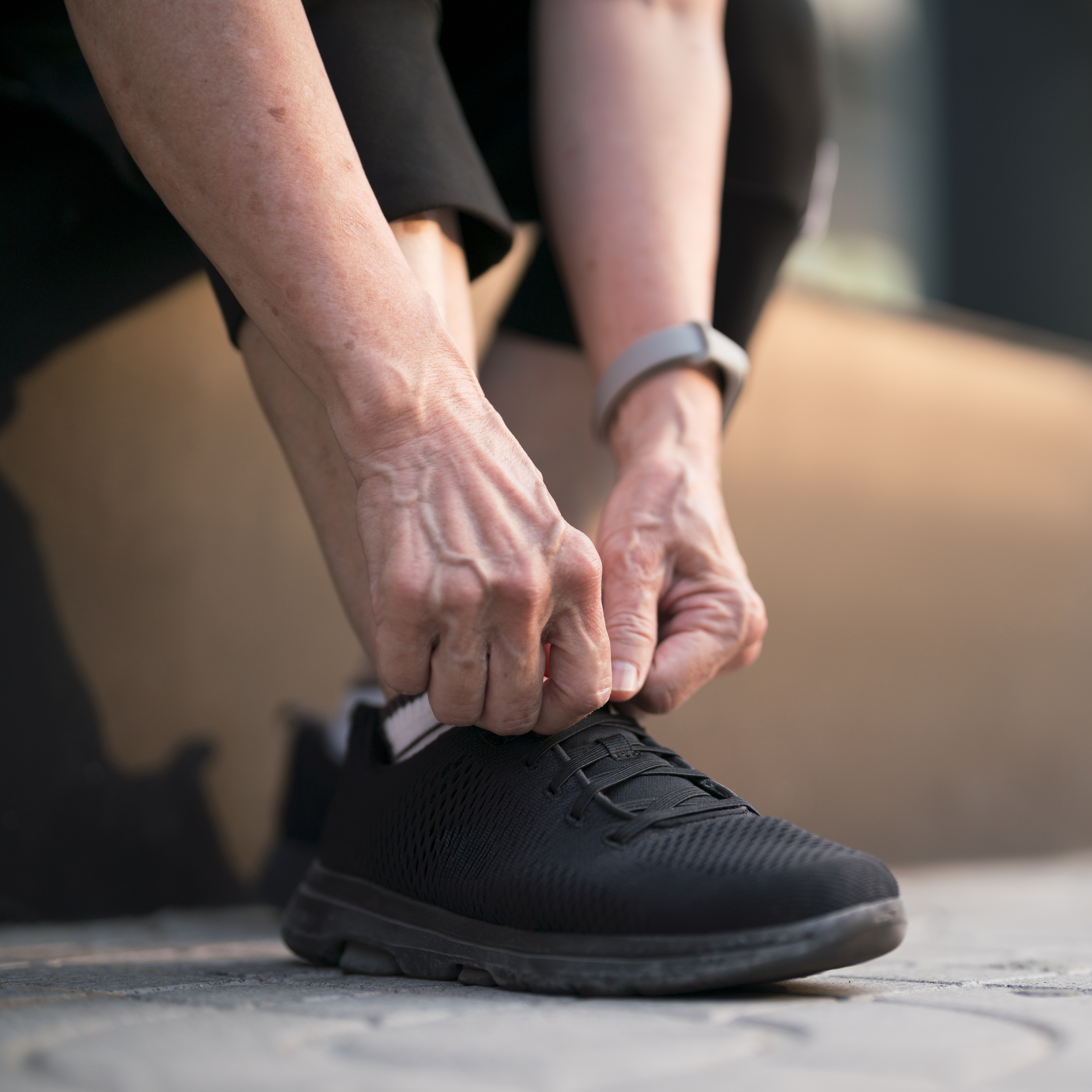 closeup of woman tying black shoe wearing new supportive footwear after finding out how to prevent arthritis