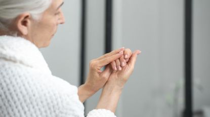 mature woman inspecting her hands for signs of kidney disease in her nails