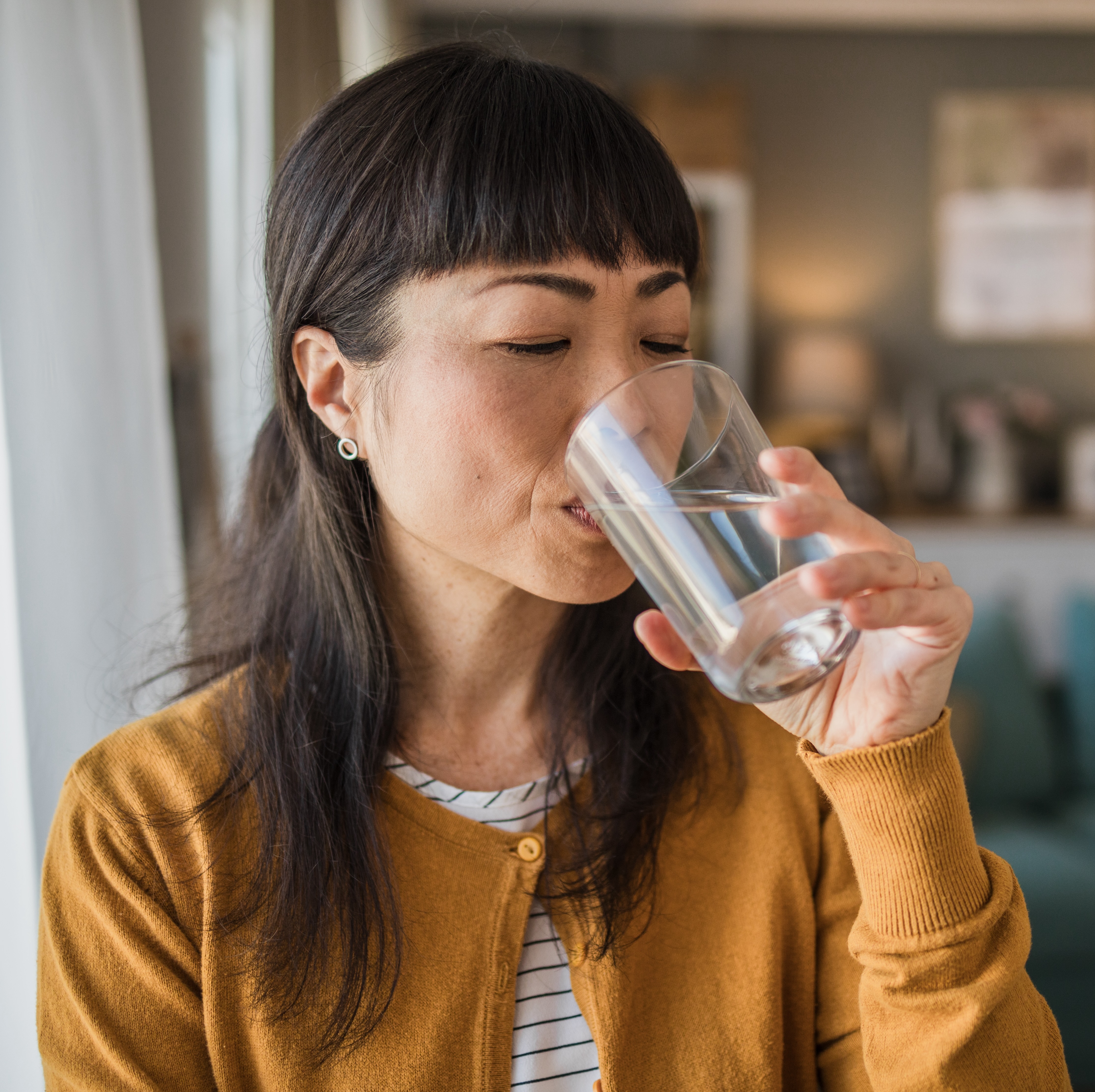 woman at home drinking from a glass of water