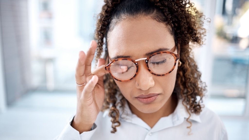 A Black woman rubbing her eyes due to thyroid eye disease symptoms