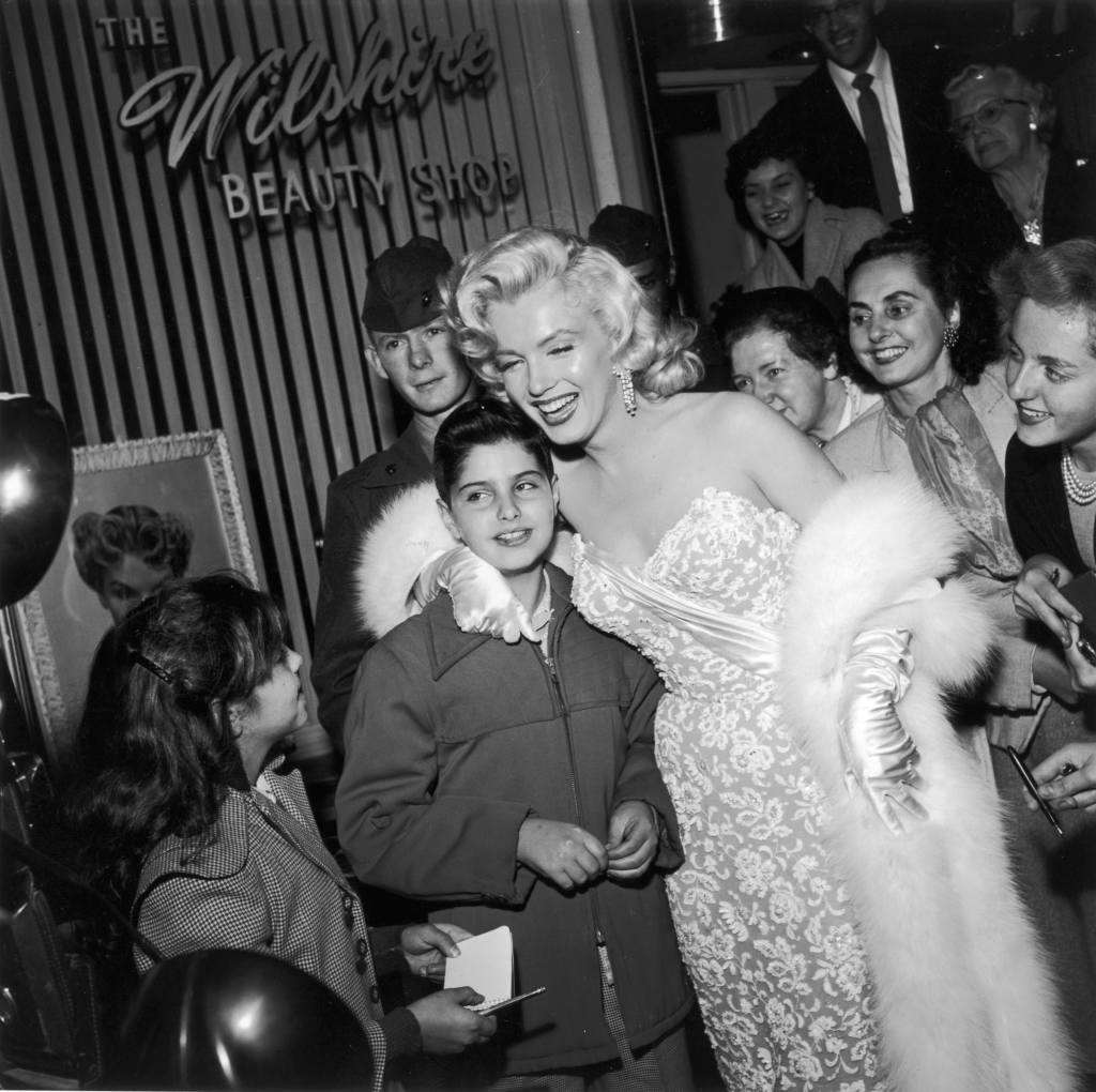 Marilyn Monroe (1926 - 1962) smiles as she poses with fans in front of the Wilshire Beauty Shop at the premiere of director Jean Negulesco's film 'How to Marry a Millionaire,' Hollywood, California