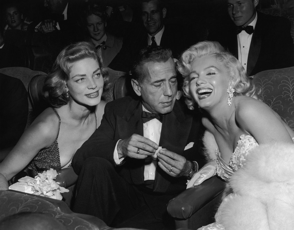 Married American actors Lauren Bacall (L) and Humphrey Bogart (1899 - 1957) pose with American actor Marilyn Monroe (1926 - 1962) at the premiere of director Jean Negulesco's film, 'How to Marry a Millionaire'