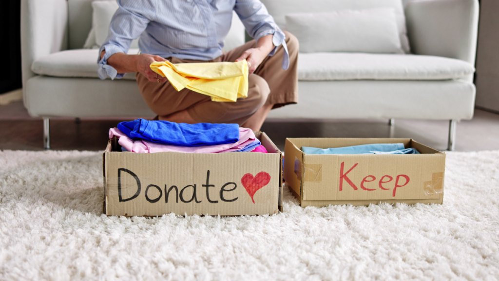 Woman places old clothes in keep and give away boxes, as she conquers clutter