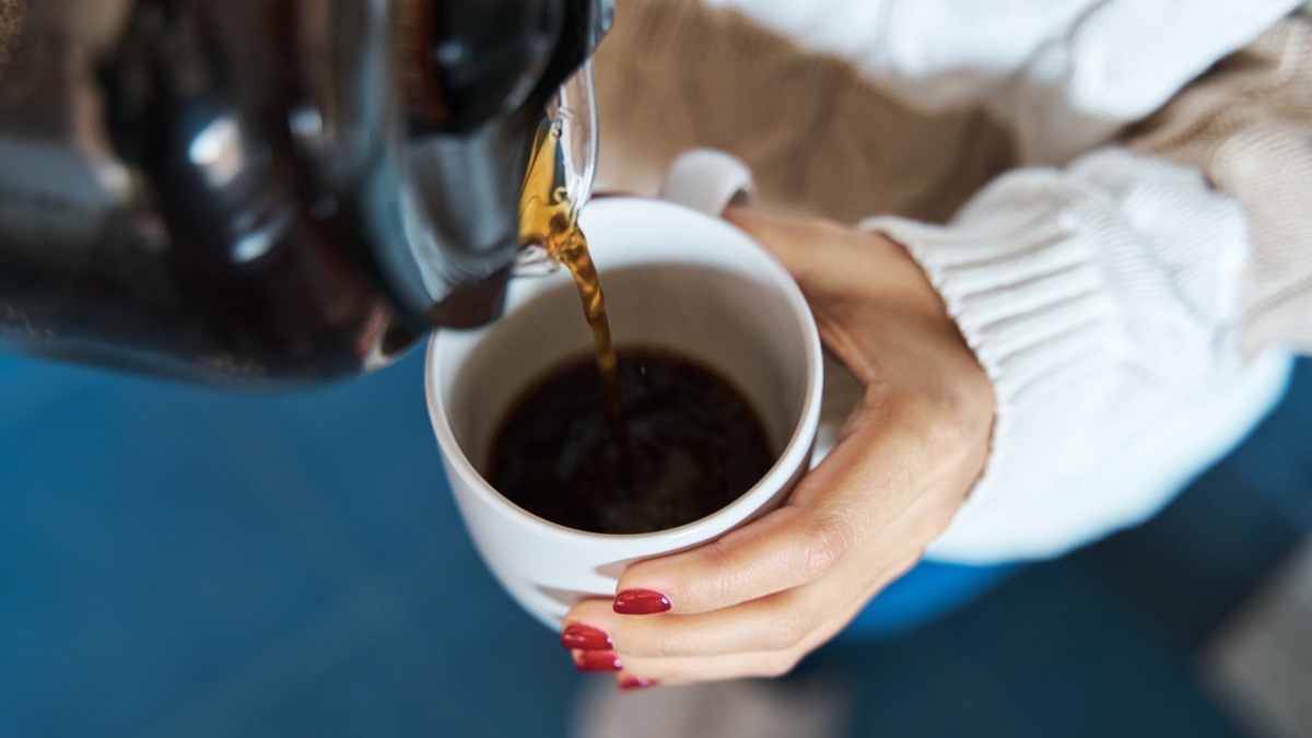 Close-up of a woman pouring a cup of coffee for healthy aging