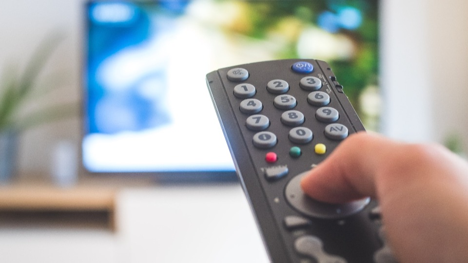 A hand holding a TV remote