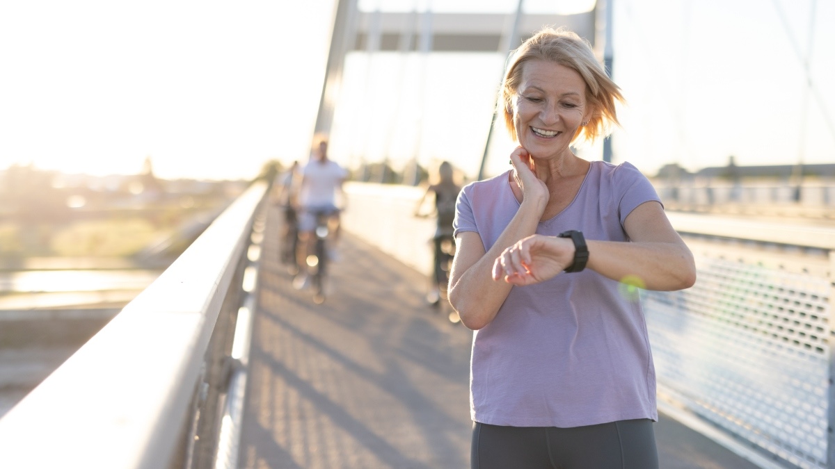 A woman out on a walk checking her heart zone while looking at her watch