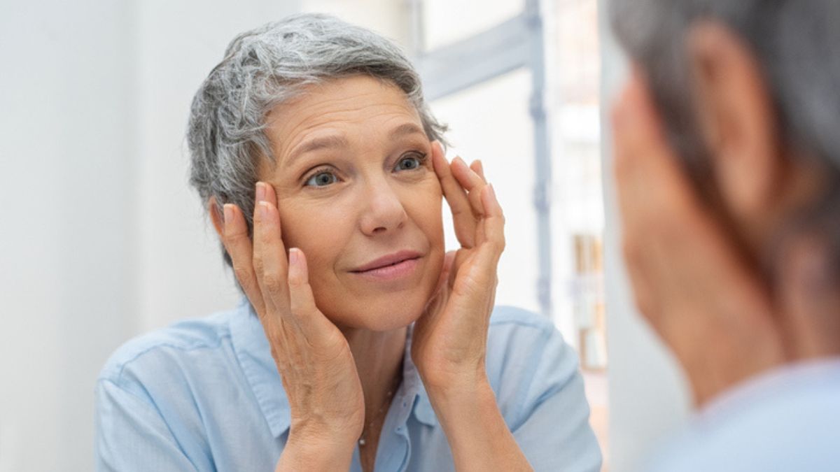 mature woman looking at her eyes in the mirror for symptoms of thyroid eye disease