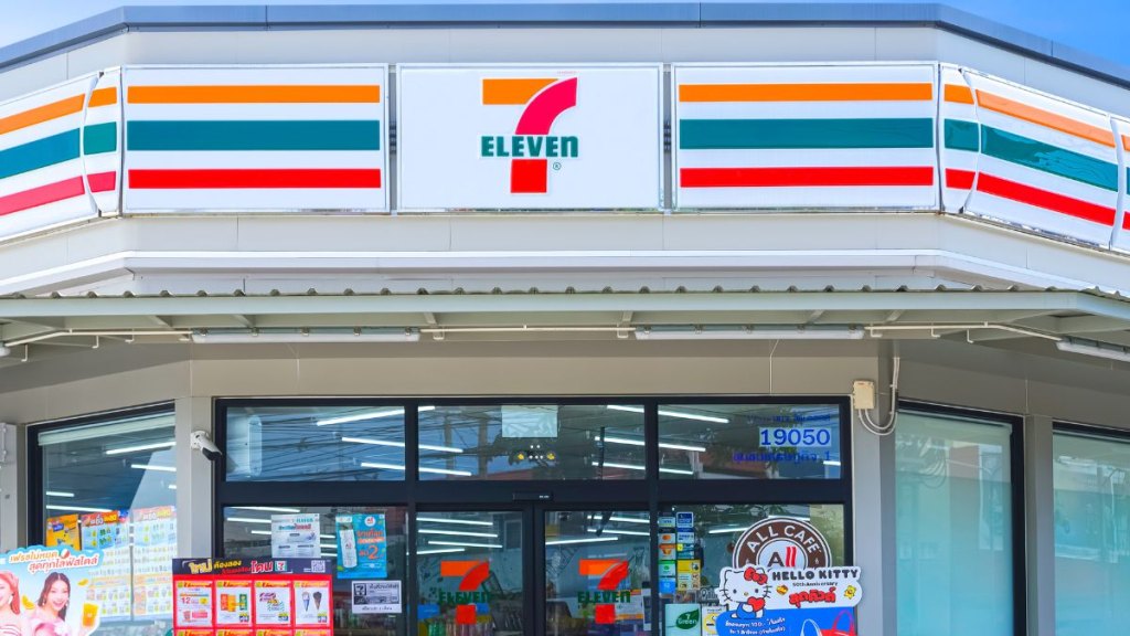 Front view of modern 7 Eleven Convenience Store Building with geometric polygonal flat slab roof against blue sky background
